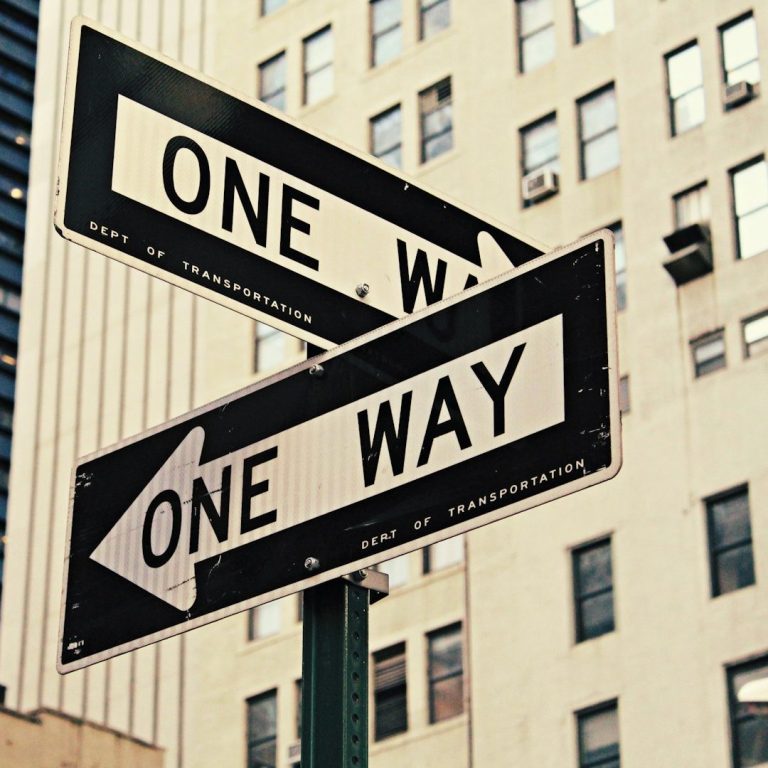 Zwei Verkehrsschilder mit der Aufschrift "One Way", die in entgegengesetzte Richtungen zeigen.